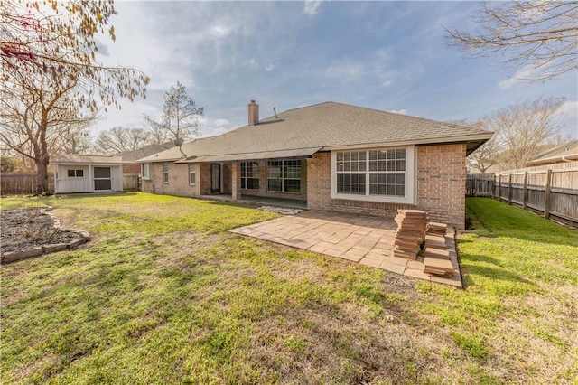 rear view of house featuring a lawn, a fenced backyard, a chimney, a patio area, and brick siding