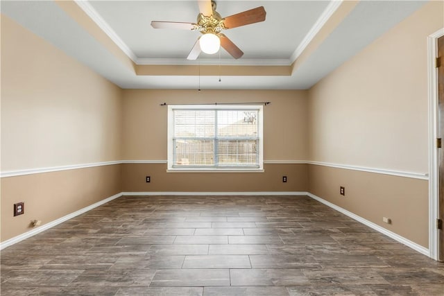 spare room featuring a tray ceiling, dark wood finished floors, and baseboards