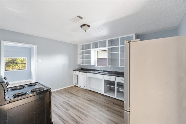 kitchen featuring white appliances, sink, a textured ceiling, and light wood-type flooring