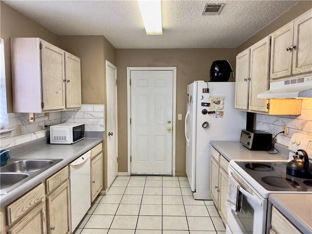 kitchen with light tile patterned flooring, sink, white appliances, light brown cabinets, and a textured ceiling