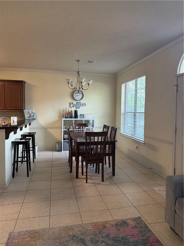 152 Forest Dr, College Station, TX 77840 - dining area with a chandelier, ornamental molding, light tile patterned flooring, and a textured ceiling