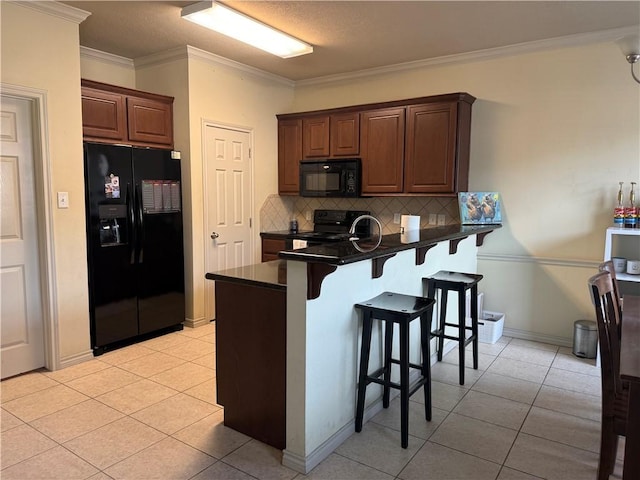 152 Forest Dr, College Station, TX 77840 - kitchen featuring black appliances, dark countertops, a breakfast bar, backsplash, and a peninsula