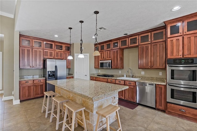 kitchen featuring visible vents, a breakfast bar, a sink, a kitchen island, and appliances with stainless steel finishes