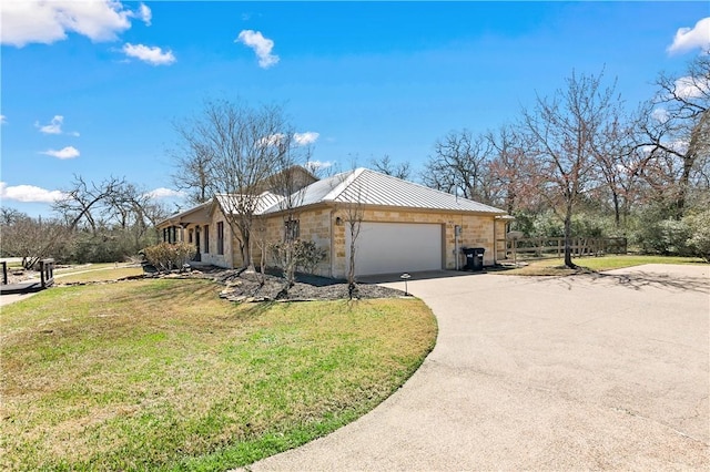 view of side of home featuring a standing seam roof, concrete driveway, stone siding, a lawn, and metal roof