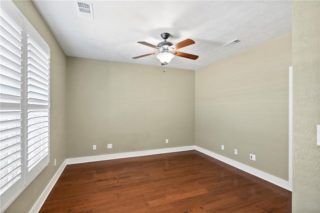 empty room with ceiling fan, visible vents, baseboards, and dark wood-style floors