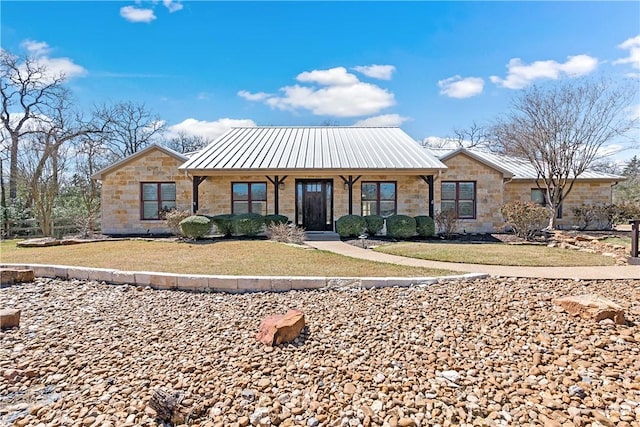 view of front of home featuring a front lawn, a porch, metal roof, stone siding, and a standing seam roof