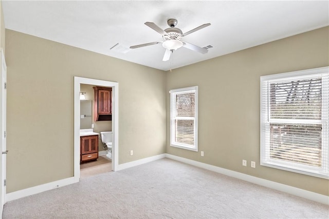 unfurnished bedroom with light carpet, ensuite bath, baseboards, and a ceiling fan