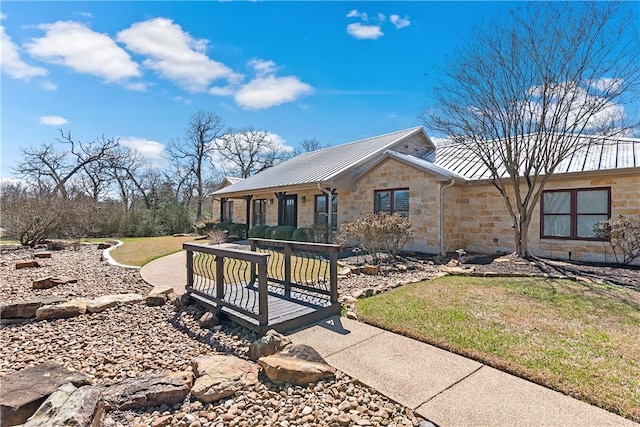 view of front of home with a front yard, stone siding, and metal roof