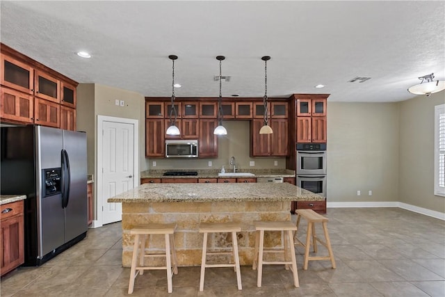 kitchen with visible vents, black appliances, a sink, a kitchen island, and a breakfast bar area