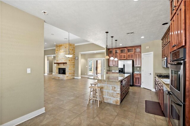 kitchen with a kitchen island, glass insert cabinets, a breakfast bar, appliances with stainless steel finishes, and a fireplace