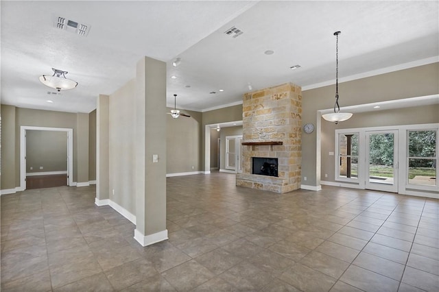 unfurnished living room featuring a stone fireplace, tile patterned floors, baseboards, and visible vents