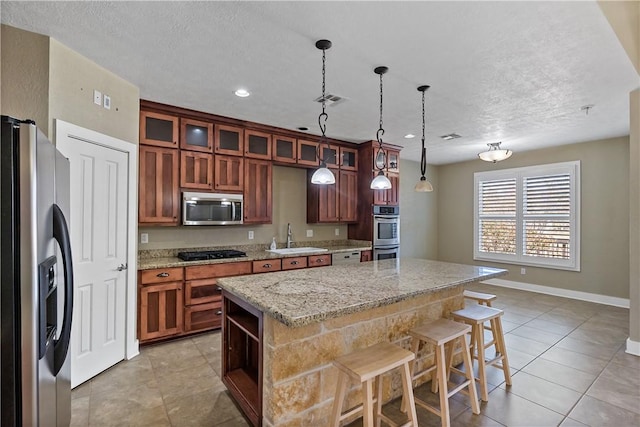 kitchen featuring visible vents, a sink, a center island, appliances with stainless steel finishes, and hanging light fixtures