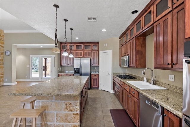 kitchen with visible vents, a kitchen island, stainless steel appliances, a sink, and pendant lighting