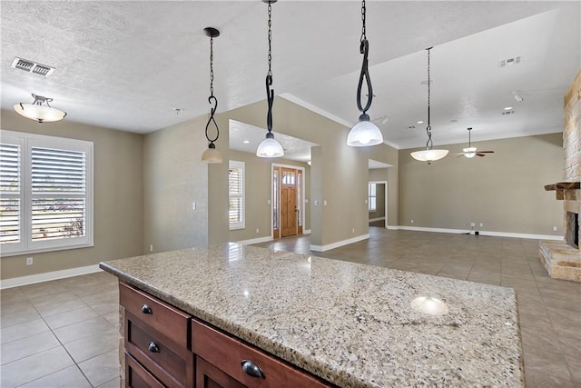 kitchen with a wealth of natural light, visible vents, a stone fireplace, and open floor plan