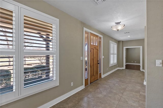 foyer entrance with visible vents and baseboards