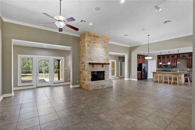 unfurnished living room with visible vents, crown molding, baseboards, a fireplace, and a sink