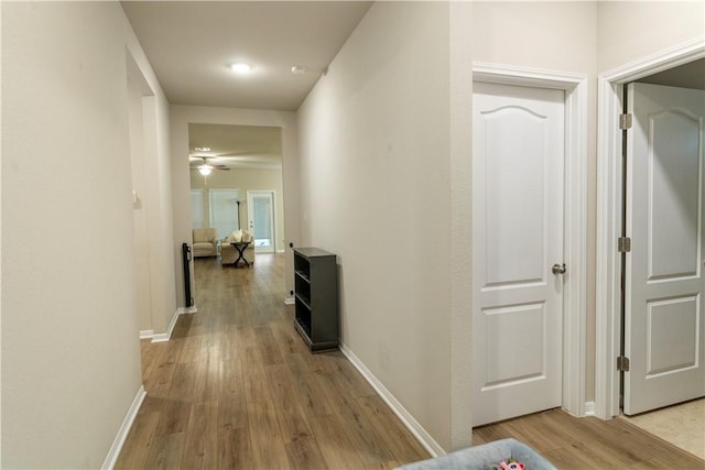 hallway with light wood-style flooring and baseboards