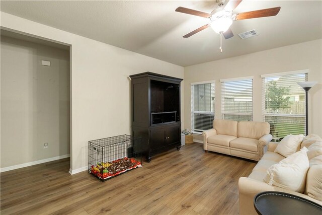 living room featuring ceiling fan, baseboards, visible vents, and wood finished floors
