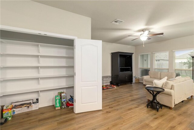 living room with ceiling fan, light wood finished floors, and visible vents