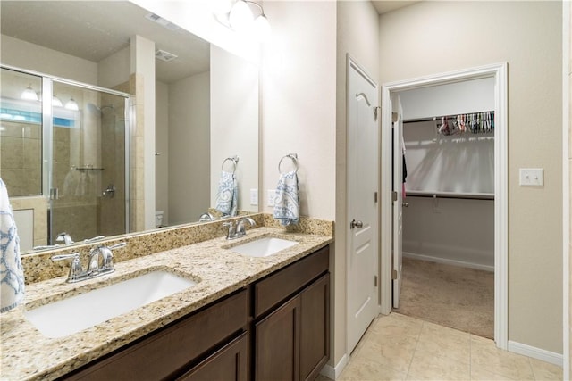 full bathroom with a sink, double vanity, a walk in closet, and a shower stall
