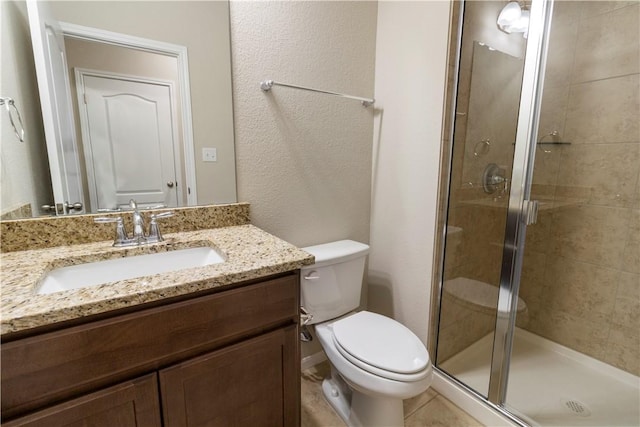 bathroom with vanity, toilet, a shower stall, and a textured wall