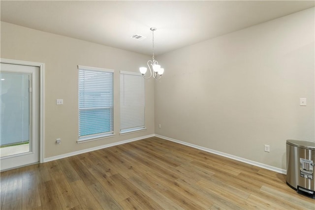 empty room featuring baseboards, an inviting chandelier, and visible vents