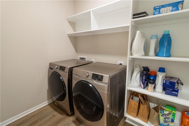 washroom with washing machine and clothes dryer, baseboards, laundry area, and wood finished floors