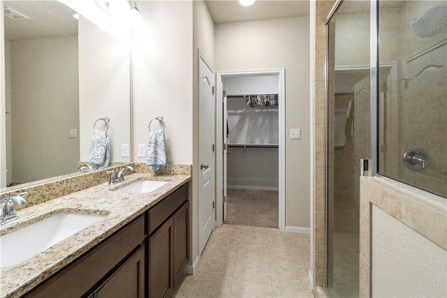 bathroom with a walk in closet, tile patterned flooring, a stall shower, and a sink