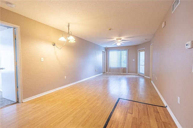 519 SW Pkwy Unit 203, College Station, TX 77840 - spare room with light wood finished floors, a chandelier, baseboards, a ceiling fan, and a textured ceiling