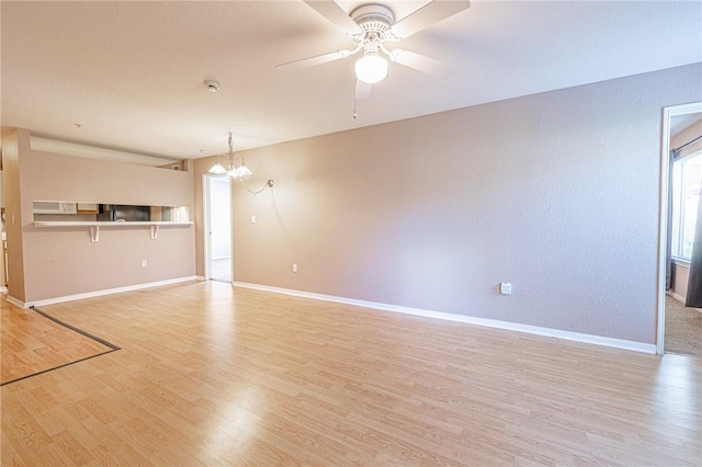519 SW Pkwy Unit 203, College Station, TX 77840 - unfurnished living room with light wood-style flooring, baseboards, a chandelier, and a ceiling fan