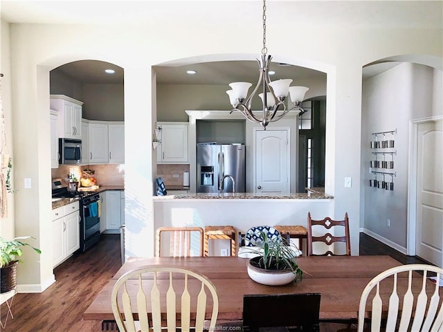 15313 Lowry Meadow Ln, College Station, TX 77845 - dining area with arched walkways, dark wood-style floors, a chandelier, baseboards, and recessed lighting