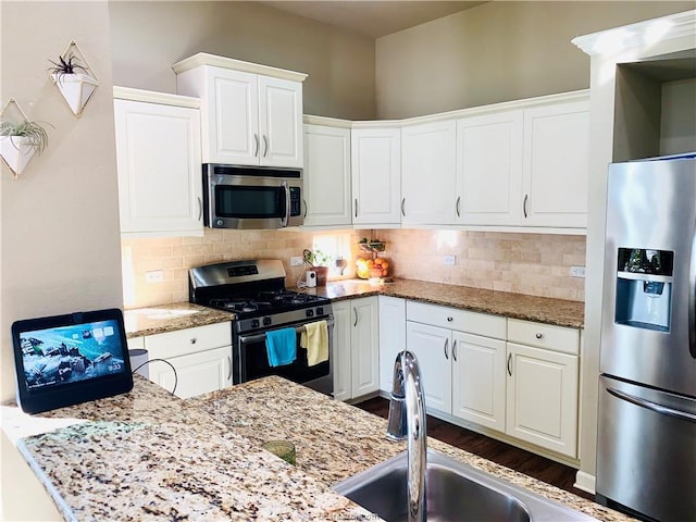 15313 Lowry Meadow Ln, College Station, TX 77845 - kitchen featuring stainless steel appliances, white cabinets, backsplash, and light stone counters
