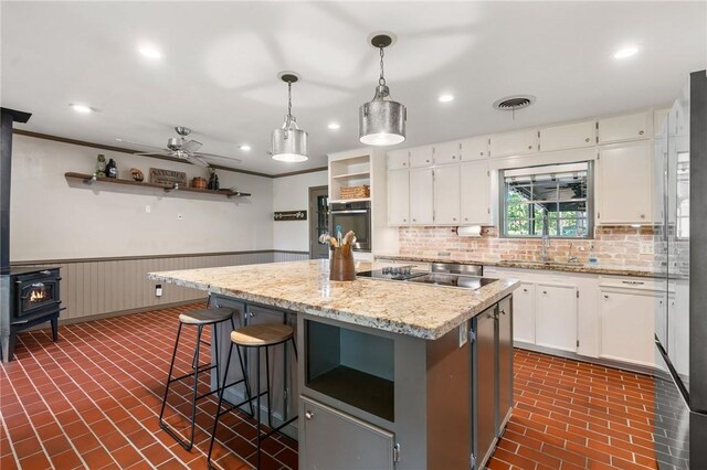 2355 Jackson League Cir, Brenham, TX 77337 - kitchen with open shelves, a sink, brick floors, black electric cooktop, and white cabinetry