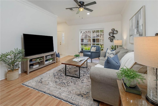 living area featuring crown molding, wood finished floors, baseboards, and ceiling fan