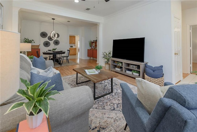 living area featuring visible vents, ornamental molding, a ceiling fan, and wood finished floors