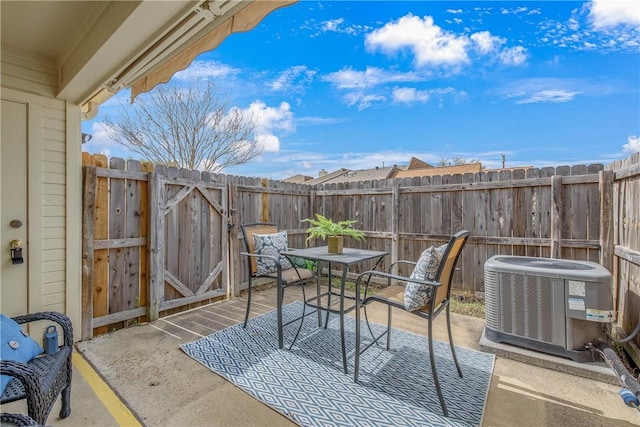 view of patio with cooling unit, outdoor dining space, and fence