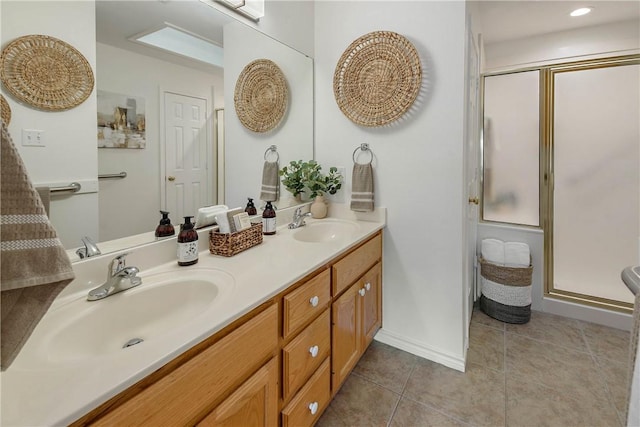 full bathroom featuring tile patterned floors, a stall shower, double vanity, and a sink