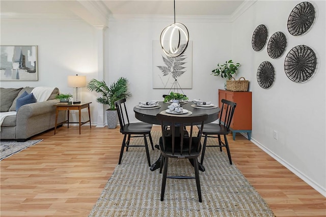 dining space with baseboards, light wood-style floors, and ornamental molding