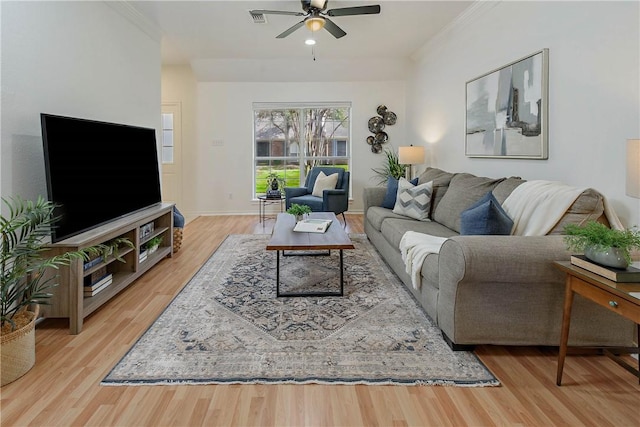 living area with visible vents, crown molding, and wood finished floors