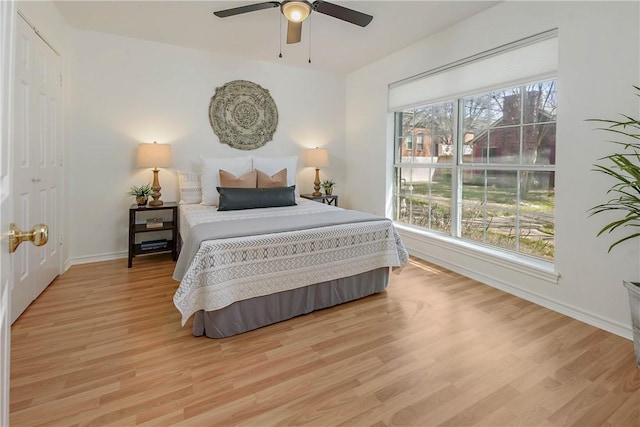 bedroom with light wood-style flooring, a ceiling fan, and baseboards