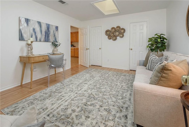 living area with visible vents, baseboards, and wood finished floors