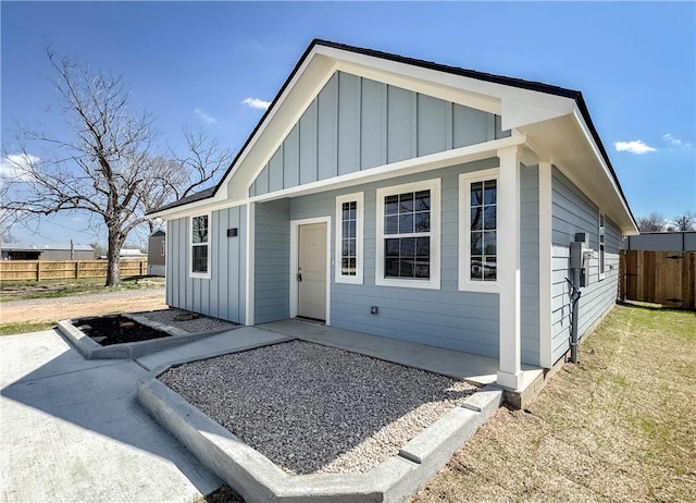 view of front of property with board and batten siding, a patio, and fence