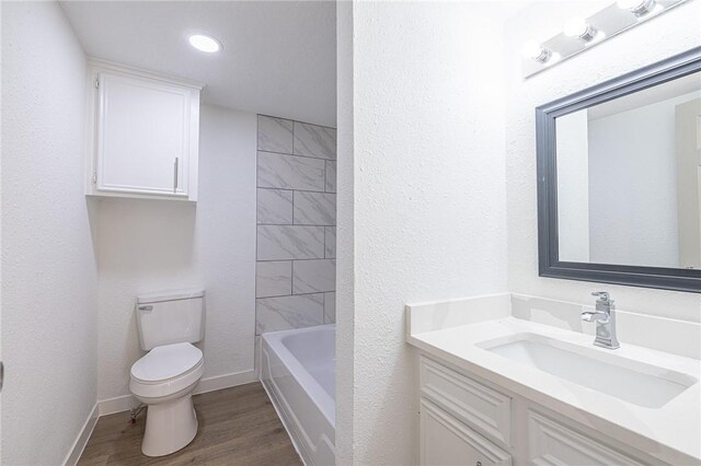 full bathroom featuring hardwood / wood-style floors, vanity, tiled shower / bath combo, and toilet