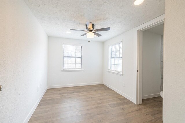 unfurnished room featuring a textured ceiling, light wood-type flooring, and ceiling fan