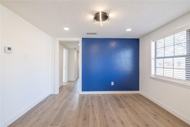 spare room featuring a textured ceiling and light hardwood / wood-style flooring