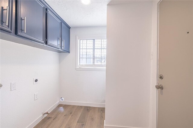 washroom with gas dryer hookup, cabinets, a textured ceiling, hookup for an electric dryer, and light hardwood / wood-style floors