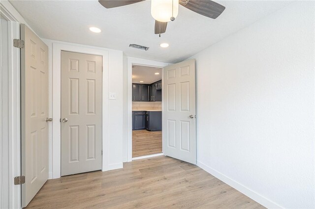 unfurnished bedroom featuring ceiling fan, light hardwood / wood-style floors, and a closet