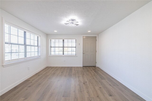 unfurnished room featuring light hardwood / wood-style floors and a textured ceiling