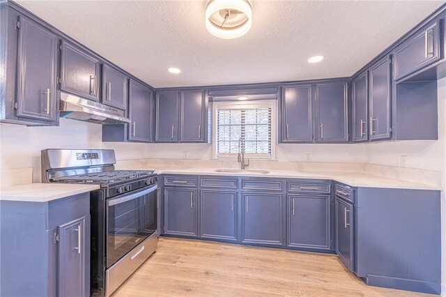 kitchen featuring sink, stainless steel gas range, light hardwood / wood-style flooring, blue cabinets, and a textured ceiling