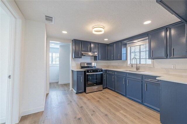 kitchen featuring blue cabinetry, stainless steel gas range oven, sink, and plenty of natural light